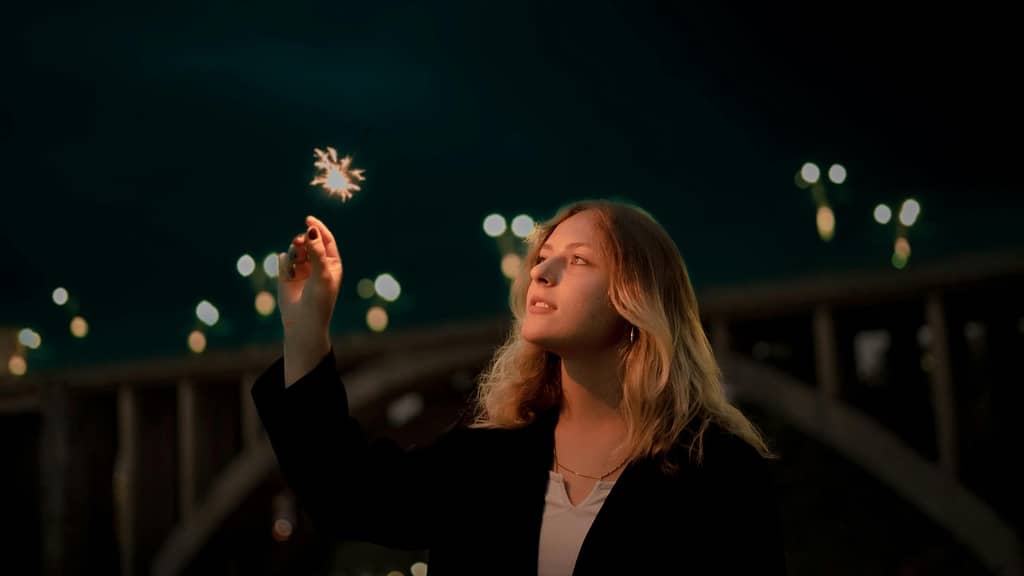 A beautiful woman at night holding a sparkling fire - as a symbol in a men's recurring dream.