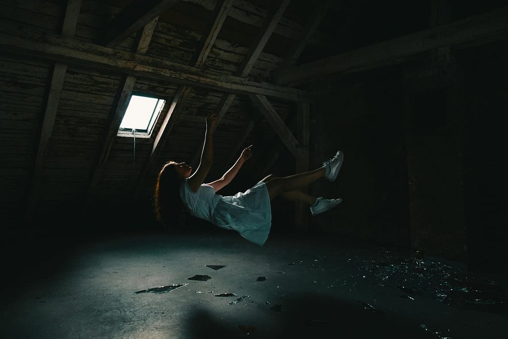 A woman fast asleep who is experience a feeling as she is falling deep down
