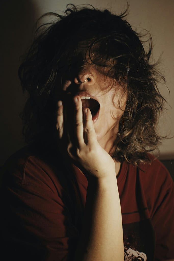 A woman yawning due to chronic sleep deprivation