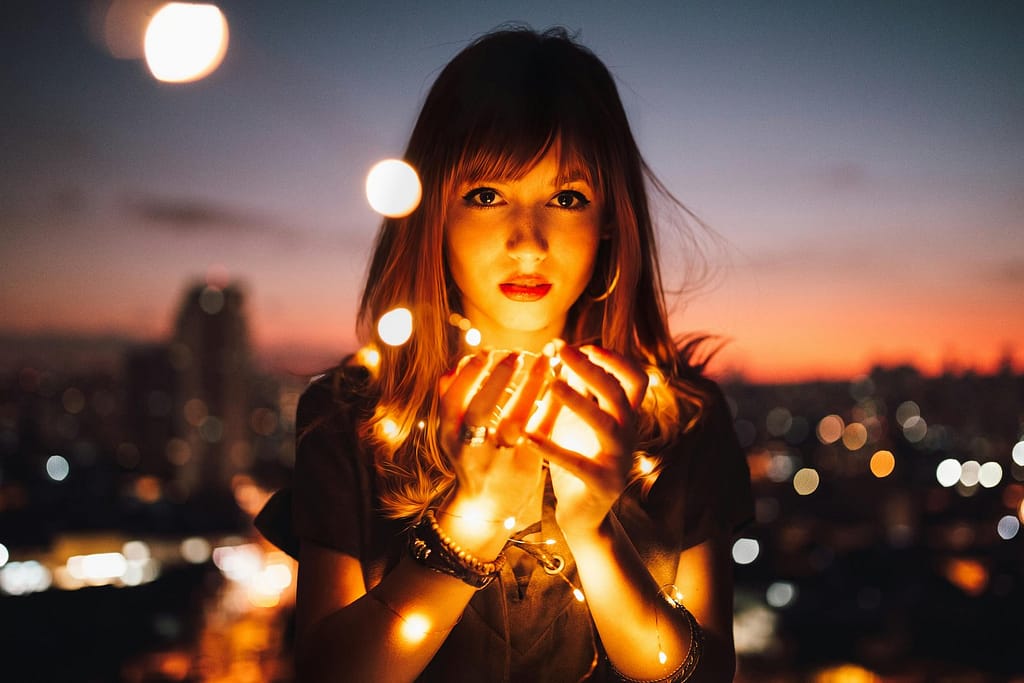 A woman holding a strings of lamps in her hands.