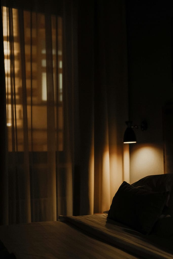 An image of an empty bed at a discrete night lamp.